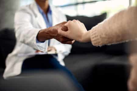 plan rapproche du psychotherapeute et de son patient tenant des mains pendant une session