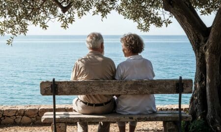 un couple profitant de la vue sur la mer depuis un banc sous un arbre