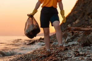 benevole ramassant des dechets sur la plage par beau temps